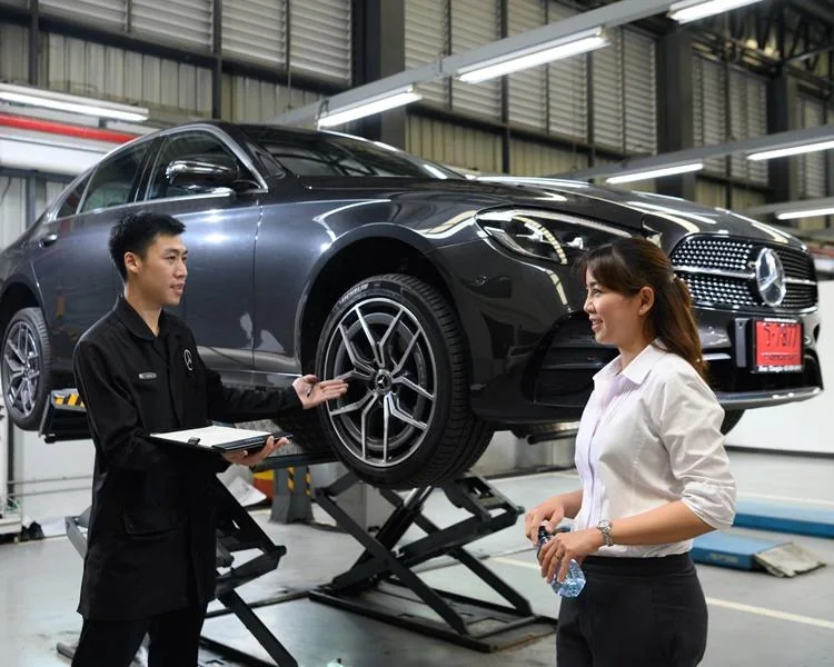 Service advisor speaking with a customer beside a car on a lift